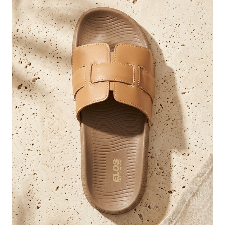 Tan slide sandal with 'Elos' branding on a textured beige surface